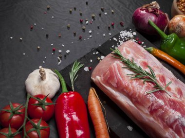 Biberiye, sebze ve baharatlar ile kesme tahtası üzerinde çiğ domuz eti.