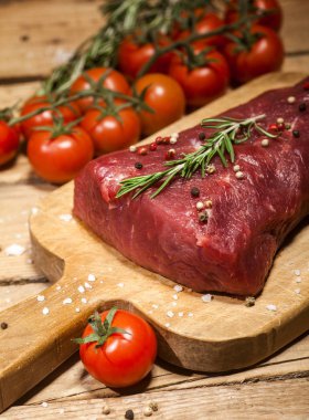 Bir kesme tahtası biberiye ve baharatlar ile ham sığır eti biftek.