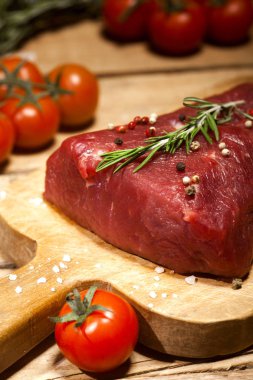 Bir kesme tahtası biberiye ve baharatlar ile ham sığır eti biftek.