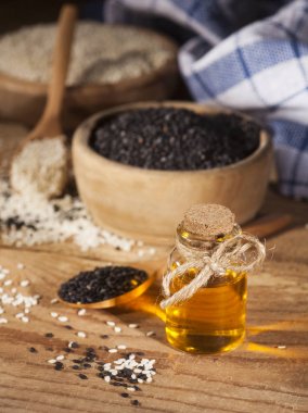 Cam şişe ve beyaz ve siyah tohumlar ahşap kase taze susam yağı