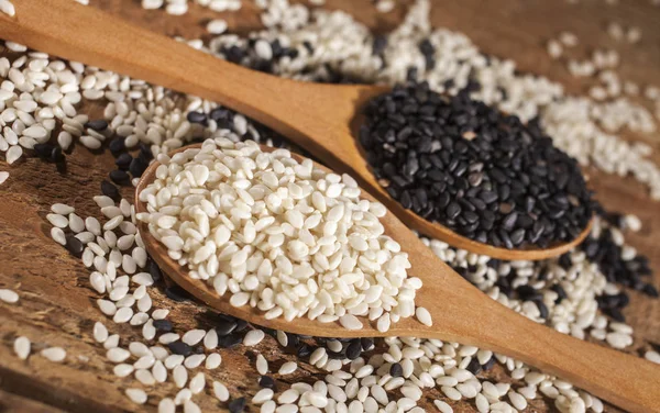 Fresh black and white sesame seeds in spoons — Stock Photo, Image