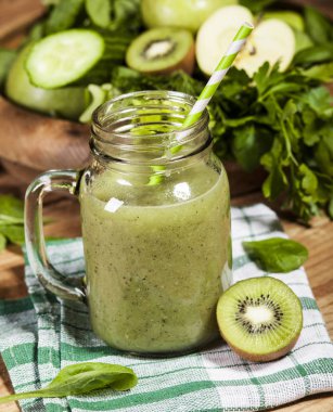 Cam pipet ile taze karıştırılmış yeşil smoothie. Ahşap arka plan.