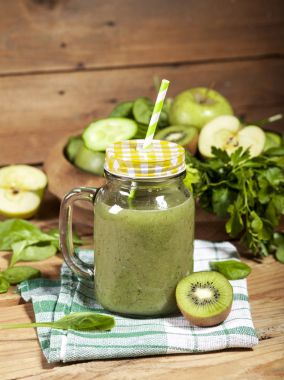 Cam pipet ile taze karıştırılmış yeşil smoothie. Ahşap arka plan.