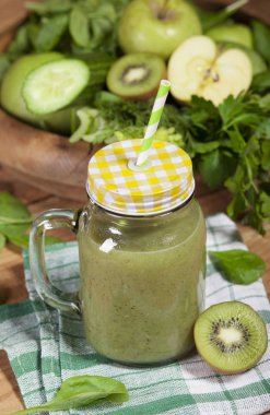 Cam pipet ile taze karıştırılmış yeşil smoothie. Ahşap arka plan.