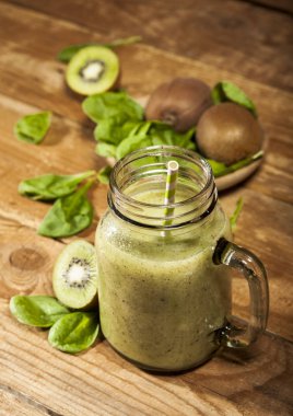 Cam pipet ile taze karıştırılmış yeşil smoothie. Ahşap arka plan.