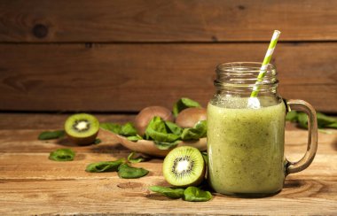 Cam pipet ile taze karıştırılmış yeşil smoothie. Ahşap arka plan.