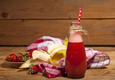 Çilek ve muz smoothie veya milkshake şişe ahşap arka plan üzerinde.