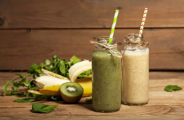 Batidos verdes y plátanos recién mezclados en botellas de vidrio con pajitas . — Foto de Stock