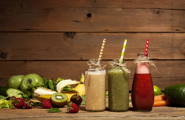 Ассортимент фруктово-овощных коктейлей в стеклянных бутылках с соломинками — стоковое фото