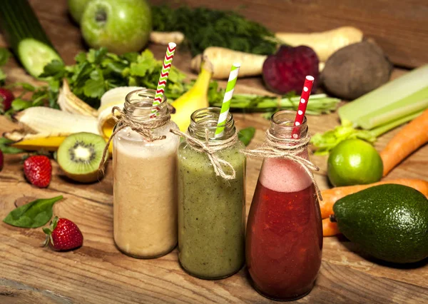 Assortment of fruit and vegetable smoothies in glass bottles with straws — Stock Photo, Image