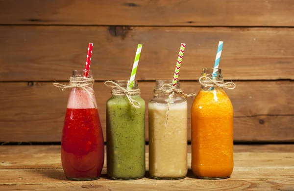 Assortimento di frullati di frutta e verdura in bottiglie di vetro con cannucce — Foto Stock