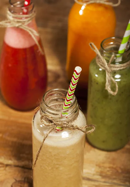 Assortment of fruit and vegetable smoothies in glass bottles with straws — Stock Photo, Image