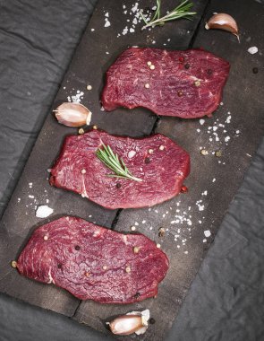Bir kesme tahtası biberiye ve baharatlar ile ham sığır eti biftek.