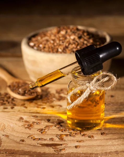 Льняное масло, ложка и миска льняных семян на деревянном фоне — стоковое фото