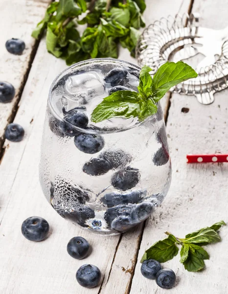 Bebida fría de verano con arándanos, menta y hielo sobre fondo de madera blanca — Foto de Stock