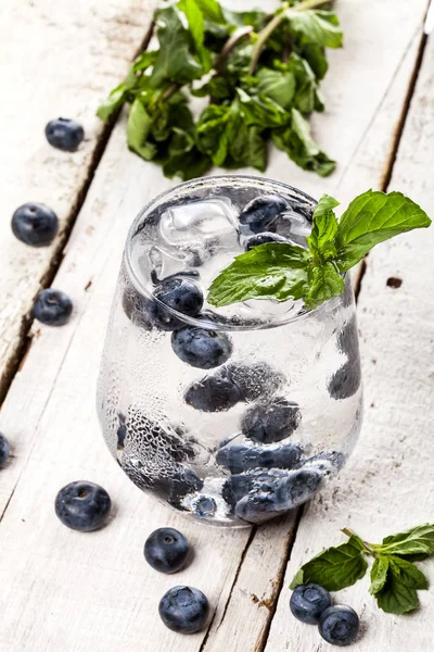 Bebida fría de verano con arándanos, menta y hielo sobre fondo de madera blanca — Foto de Stock