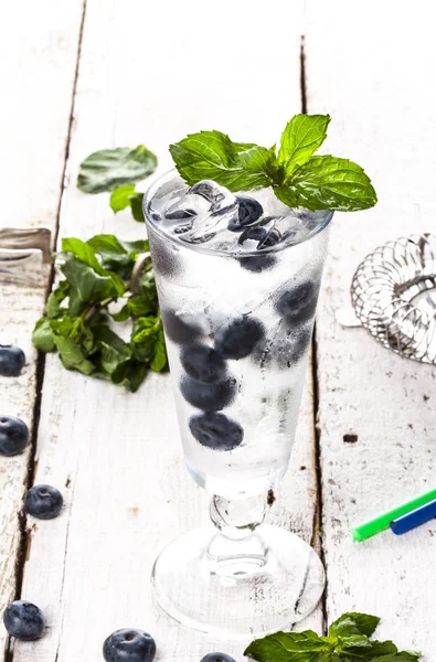 Bebida fría de verano con arándanos, menta y hielo sobre fondo de madera blanca — Foto de Stock
