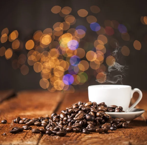 Tasse à café et grains de café sur une table en bois et fond bokeh — Photo