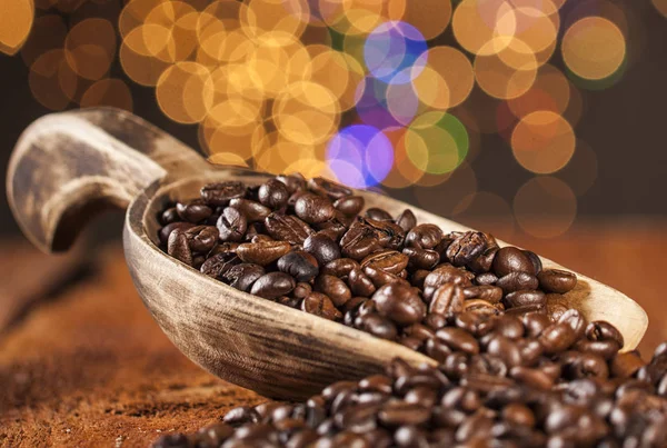 Wooden spoon with coffee beans on a wooden table and bokeh background — Stock Photo, Image