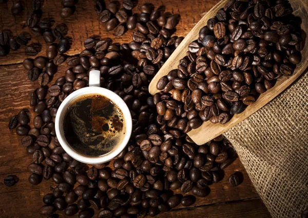 Tasse à café et sac avec des grains de café sur une table en bois. Vue du dessus . — Photo