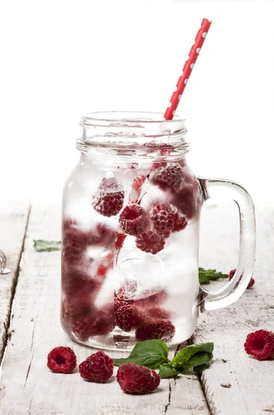Kaldtdrikk med bringebær, mynte og is i glass på hvit bakgrunn – stockfoto