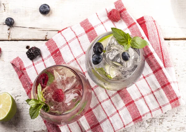 Boissons froides estivales avec framboises, mûres et bleuets sur fond blanc — Photo