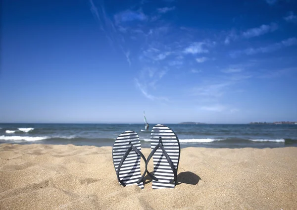Blue sandal flip flop on the sand beach with blue sea and sky background in summer vacations. Copy space — Stock Photo, Image