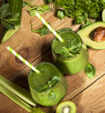 Gözlük payet ile taze karıştırılmış yeşil smoothie. Ahşap arka plan.