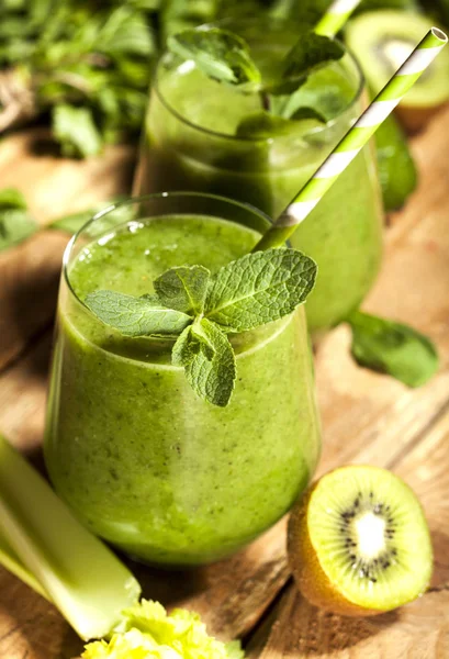 Gözlük payet ile taze karıştırılmış yeşil smoothie. Ahşap arka plan.