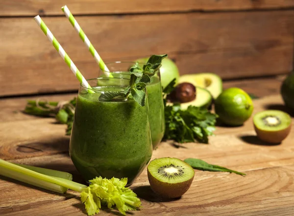 Färsk blandad grön smoothie i glas med sugrör. Trä bakgrund. — Stockfoto