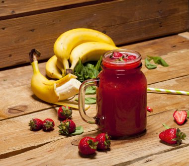 Çilek ve muz smoothie veya ahşap zemin üzerinde bir kavanoza milkshake.