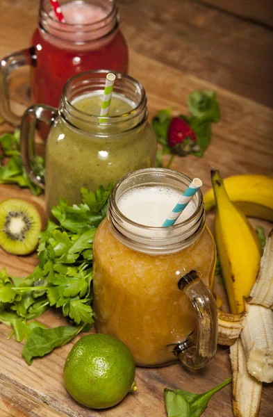 Sortiment av frukt och grönsaker smoothies i glas burkar med sugrör — Stockfoto