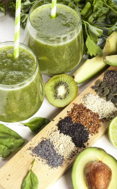 Gözlük payet ile taze karıştırılmış yeşil smoothie. Beyaz ahşap zemin.