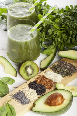 Gözlük payet ile taze karıştırılmış yeşil smoothie. Beyaz ahşap zemin.