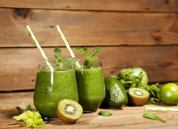 Gözlük payet ile taze karıştırılmış yeşil smoothie. Ahşap arka plan.