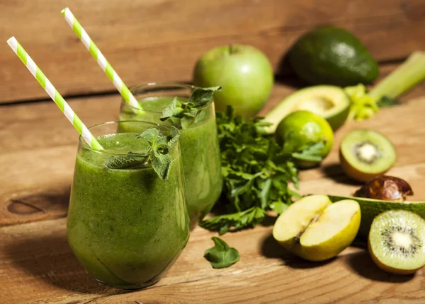 Gözlük payet ile taze karıştırılmış yeşil smoothie. Ahşap arka plan.