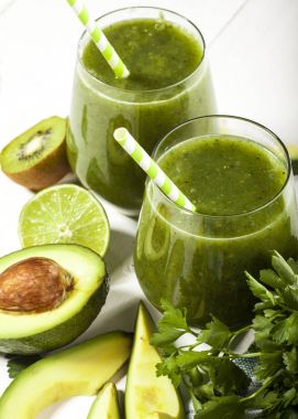 Gözlük payet ile taze karıştırılmış yeşil smoothie. Beyaz ahşap zemin.