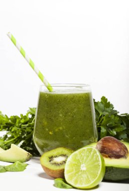 Saman ile bir bardak taze karıştırılmış yeşil smoothie. Beyaz ahşap zemin.