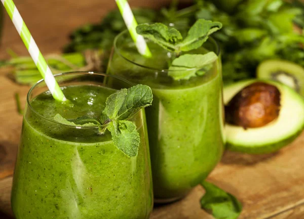 Färsk blandad grön smoothie i glas med sugrör. Trä bakgrund. — Stockfoto