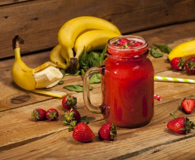 Çilek ve muz smoothie veya ahşap zemin üzerinde bir kavanoza milkshake.