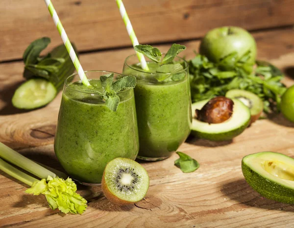 Batido verde recién mezclado en vasos con pajitas. Fondo de madera . — Foto de Stock