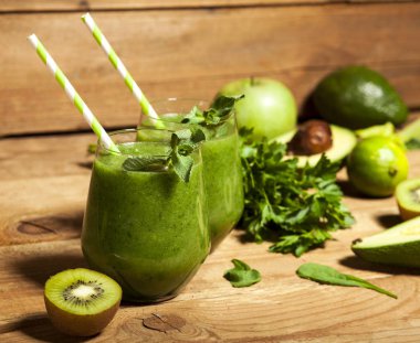 Gözlük payet ile taze karıştırılmış yeşil smoothie. Ahşap arka plan.