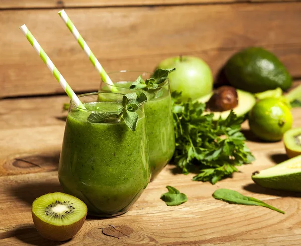 Gözlük payet ile taze karıştırılmış yeşil smoothie. Ahşap arka plan.