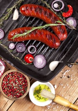 Ahşap arka plan üzerinde bir tavada ızgara sosis
