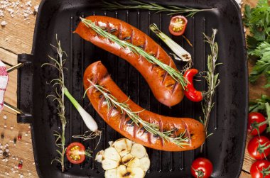 Ahşap arka plan üzerinde bir tavada ızgara sosis