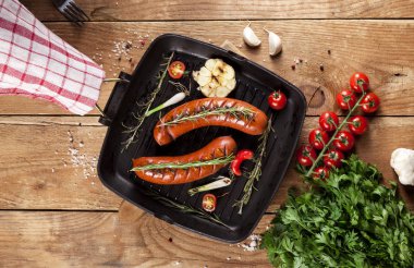 Ahşap arka plan üzerinde bir tavada ızgara sosis