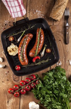 Ahşap arka plan üzerinde bir tavada ızgara sosis