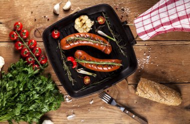 Ahşap arka plan üzerinde bir tavada ızgara sosis