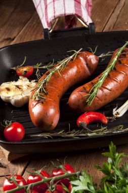 Ahşap arka plan üzerinde bir tavada ızgara sosis