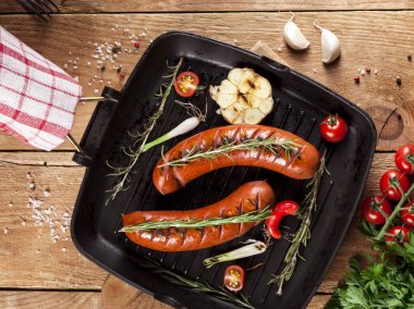 Ahşap arka plan üzerinde bir tavada ızgara sosis